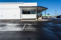 an empty parking lot with no people inside it and a man walking to the building