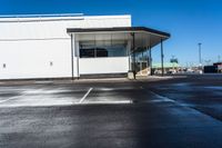 an empty parking lot with no people inside it and a man walking to the building