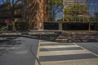 a crosswalk at an intersection near a building and trees in the background on a sunny day