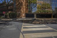 a crosswalk at an intersection near a building and trees in the background on a sunny day