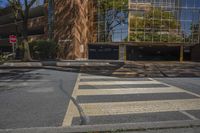 a crosswalk at an intersection near a building and trees in the background on a sunny day