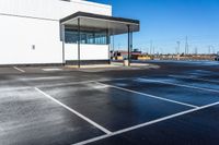 a parking lot with a white building on the left and a water gun in the middle