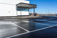 a parking lot with a white building on the left and a water gun in the middle