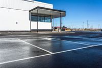 a parking lot with a white building on the left and a water gun in the middle