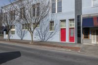 a very bright blue building with red doors and windows on a sunny day on the side of the road