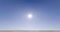 two people on snowmobiles look up at the sun over the sand area of a vast plain