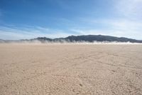 the sun is shining on the dried up desert in the distance, and mountains, covered with clouds