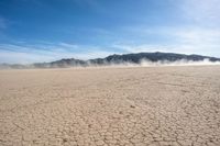 the sun is shining on the dried up desert in the distance, and mountains, covered with clouds