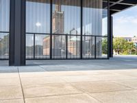 a view of the clock tower out of a glass building on a sunny day in an open courtyard