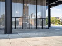 a view of the clock tower out of a glass building on a sunny day in an open courtyard