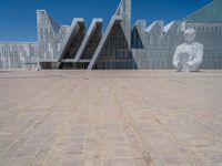 a white building with several steps and large glass panels in the facade is a mosaic that depicts a man