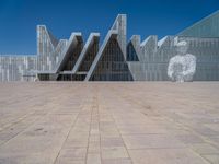 a white building with several steps and large glass panels in the facade is a mosaic that depicts a man