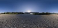 view into the fish eye lens with a sun over some bridges and trees in the background