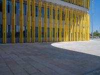 a concrete structure made into rows of orange and yellow poles are on a cement sidewalk