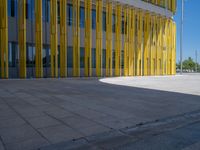 a concrete structure made into rows of orange and yellow poles are on a cement sidewalk