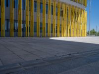 a concrete structure made into rows of orange and yellow poles are on a cement sidewalk