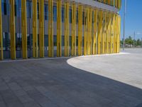 a concrete structure made into rows of orange and yellow poles are on a cement sidewalk