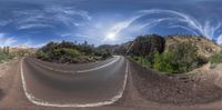 a wide angle fisheye image of a highway in the mountains looking up at a bend