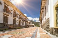 an empty street between two buildings and the sun shining through the windows in spain's central