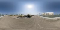 a 360 - fisheye image of an empty dirt road and a park area with lots of water