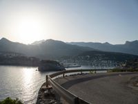 curved road along the coastline with a city in the background at sunset or dawn over a mountain town