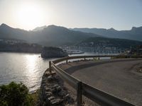 curved road along the coastline with a city in the background at sunset or dawn over a mountain town