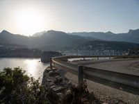 curved road along the coastline with a city in the background at sunset or dawn over a mountain town