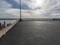 the dock and the water from which one is parked on the pier, with a bird flying in the distance