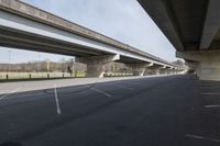 the view of an underpass with cars driving below it and empty parking lots underneath