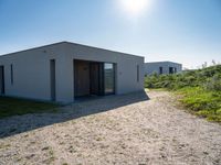 small house with flat roof sitting on grass field next to building with sliding glass doors