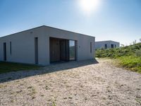 small house with flat roof sitting on grass field next to building with sliding glass doors