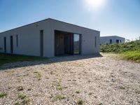 small house with flat roof sitting on grass field next to building with sliding glass doors