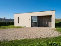 small house with flat roof sitting on grass field next to building with sliding glass doors