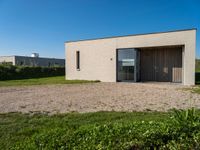 small house with flat roof sitting on grass field next to building with sliding glass doors