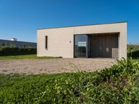 small house with flat roof sitting on grass field next to building with sliding glass doors