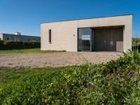 small house with flat roof sitting on grass field next to building with sliding glass doors