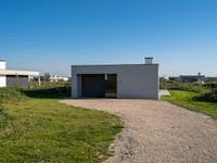 small house with flat roof sitting on grass field next to building with sliding glass doors