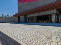 a large brick driveway that is next to a building and stairs with an empty street on the side