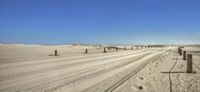 a road runs through the sand dunes behind a fenced in fenced off beach area