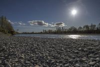 the sun shines over a river with large rocks in it on a sunny day