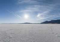 the snow has footprints in it and the sun is shining on the horizon to the mountains