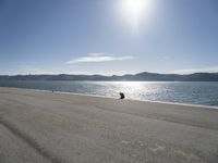 a person sitting on the beach in front of the ocean, looking at the water