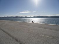 a person sitting on the beach in front of the ocean, looking at the water