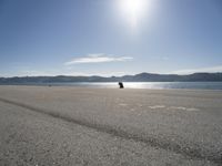 a person sitting on the beach in front of the ocean, looking at the water