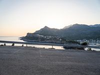 a bicycle parked near the side of a road at sunset by the water and mountain range