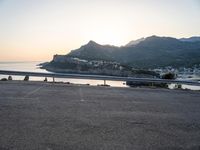 a bicycle parked near the side of a road at sunset by the water and mountain range
