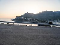 a bicycle parked near the side of a road at sunset by the water and mountain range