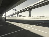 an empty parking lot and bridge from beneath it looking at the city below it with traffic lights