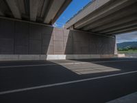 there is an empty street underneath the highway bridge near the mountain range in this picture