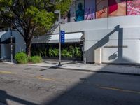 a street corner with an empty sidewalk and a building in the background with a billboard over the sidewalk that reads blue